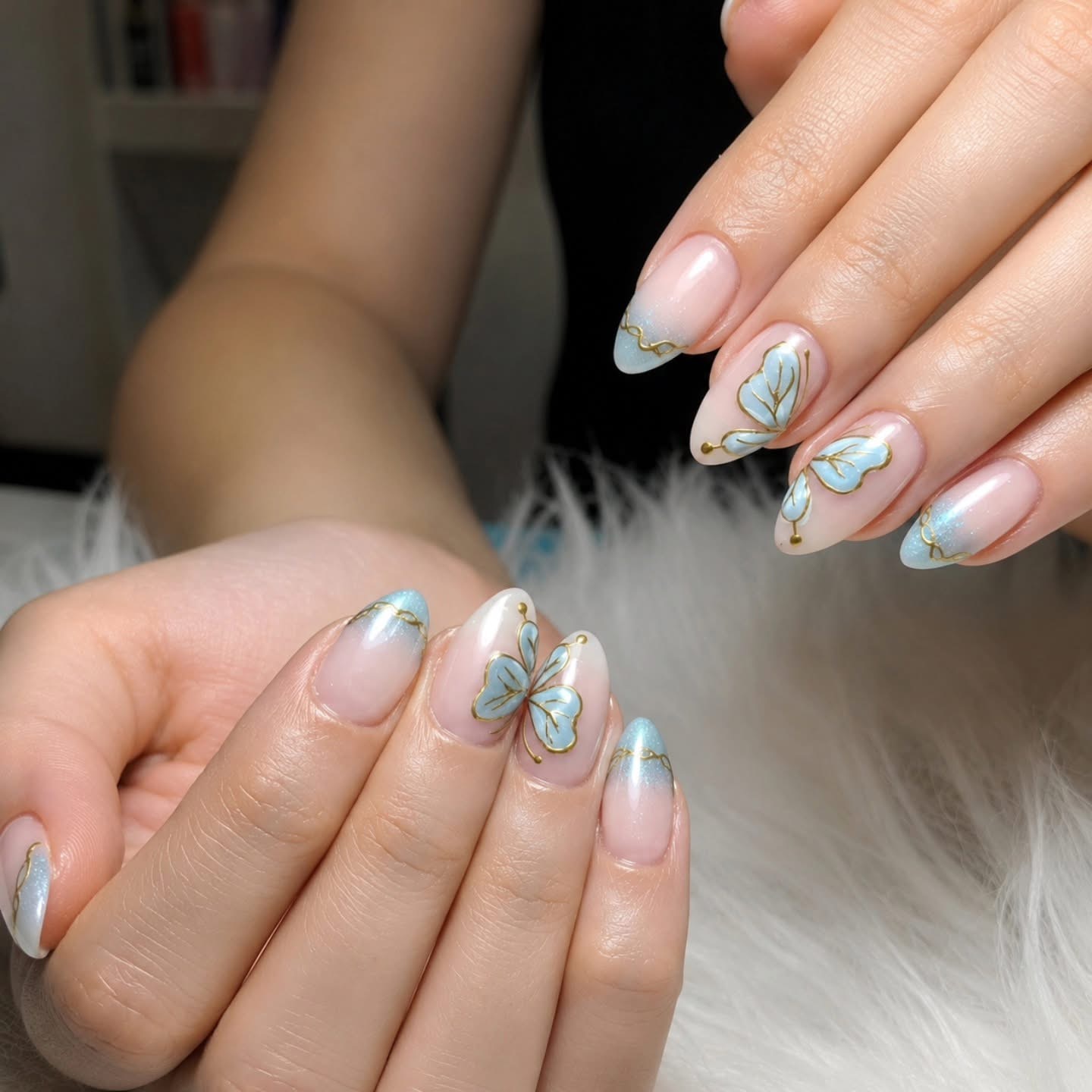 Uñas nude con mariposas azules y líneas doradas